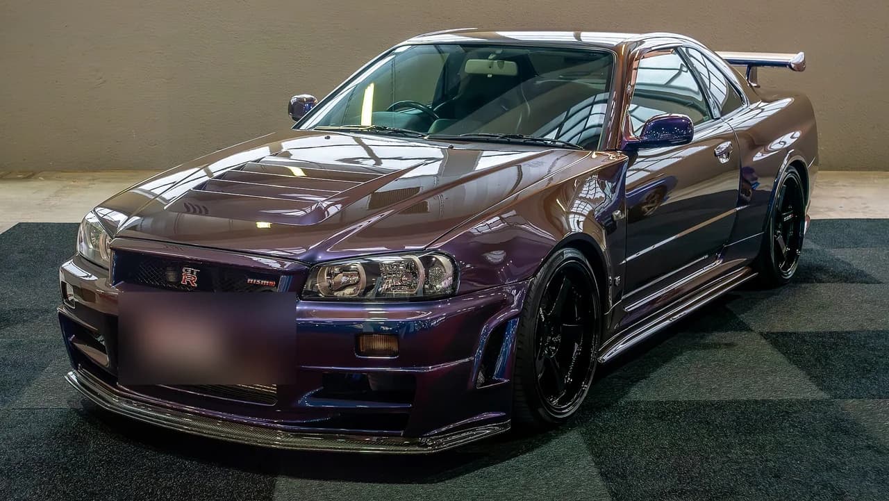 Purple Nissan Skyline GT-R R34 under studio lighting at an auto show