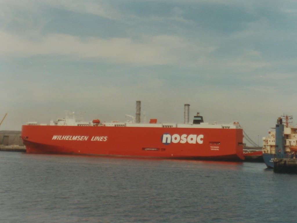 A car-carrier ship at port — the kind of vessel that ships JDM imports across the ocean
