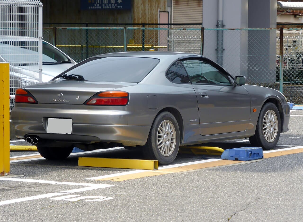 A silver Nissan Silvia Spec S (S15), rear three-quarter view in a Japanese parking area (license plate blank)