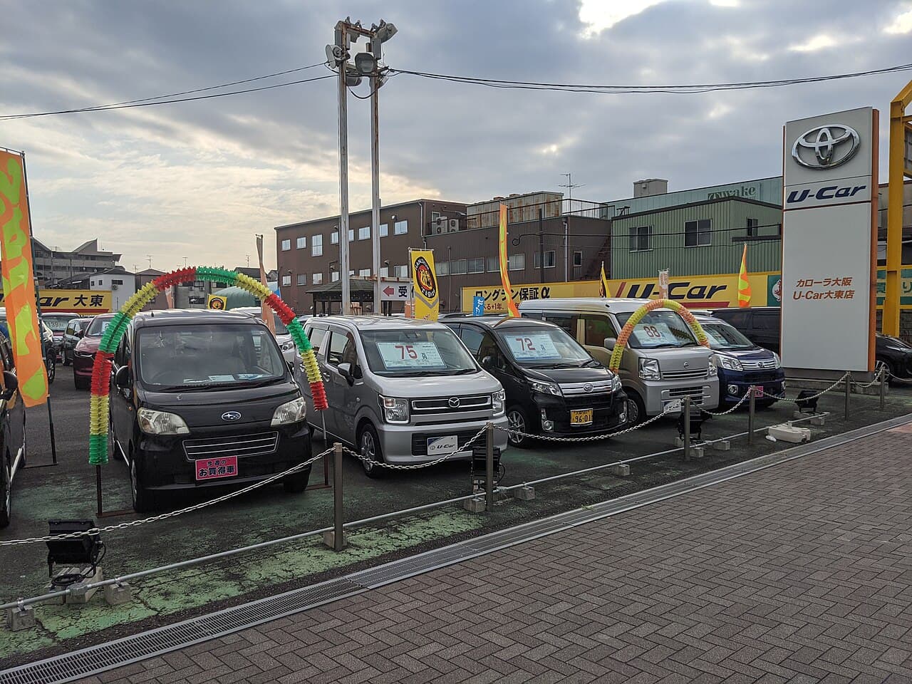 A Toyota dealership's used-car lot in Japan, cars marked with price placards — the retail end of the pipeline that starts at the auction sheet