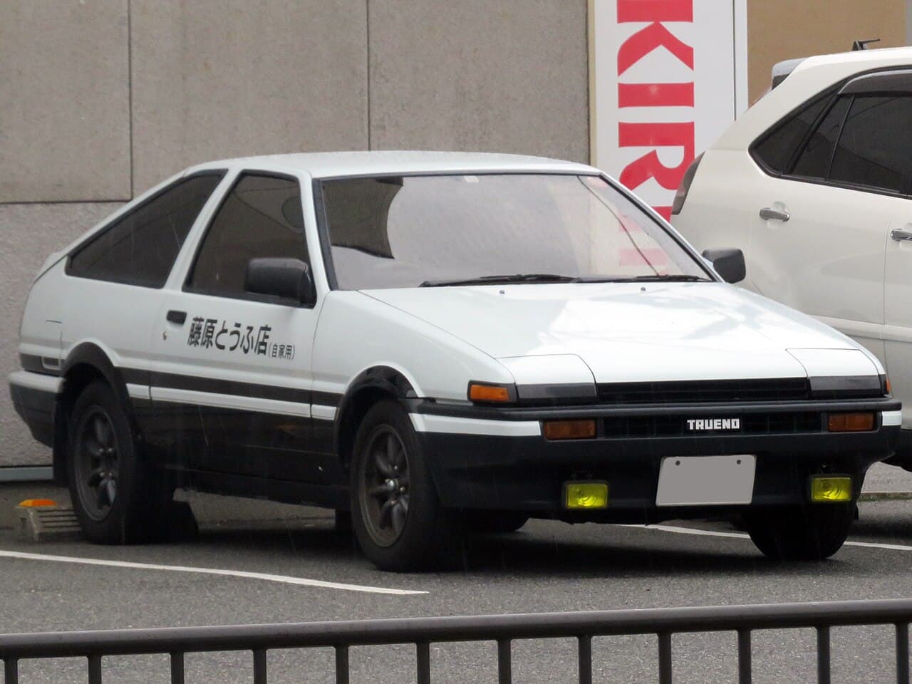 A real Toyota Sprinter Trueno AE86 in the black-and-white Initial D livery this Kyosho 1/64 model replicates